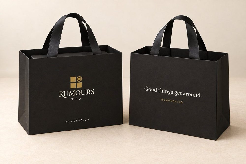 The black carrier bag, front with the Rumours Tea logo and back with the house line