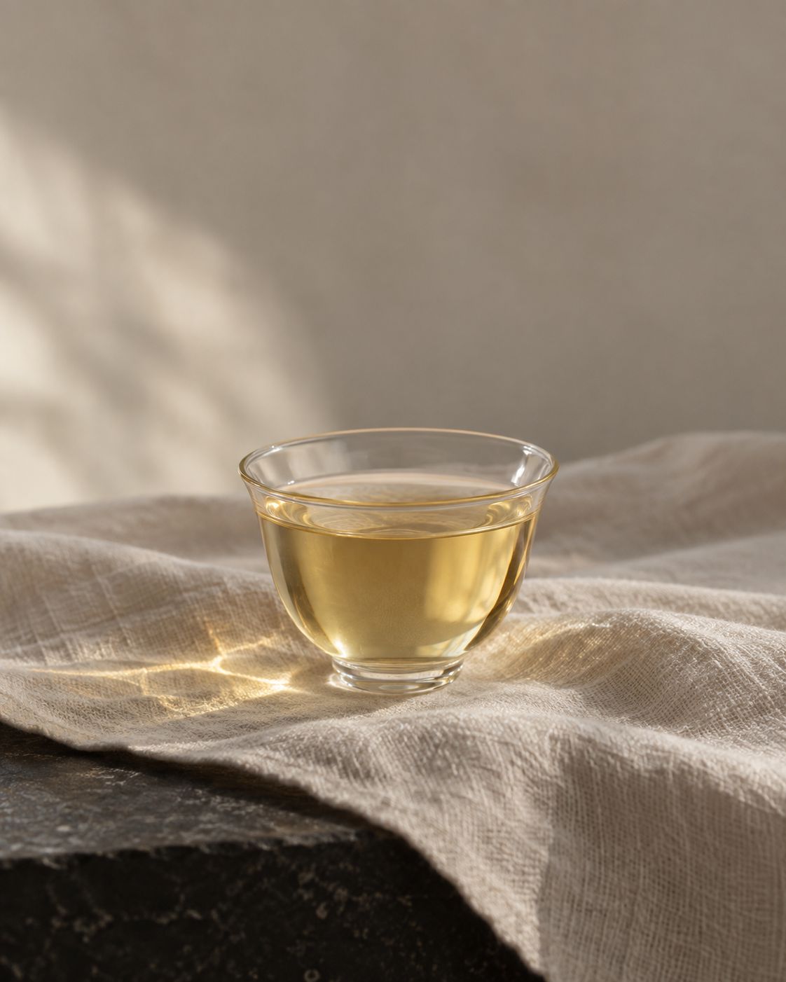 A glass cup of pale gold Silver Needle on a linen cloth